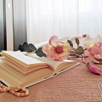 Camera glamour con libro e fiori sul letto